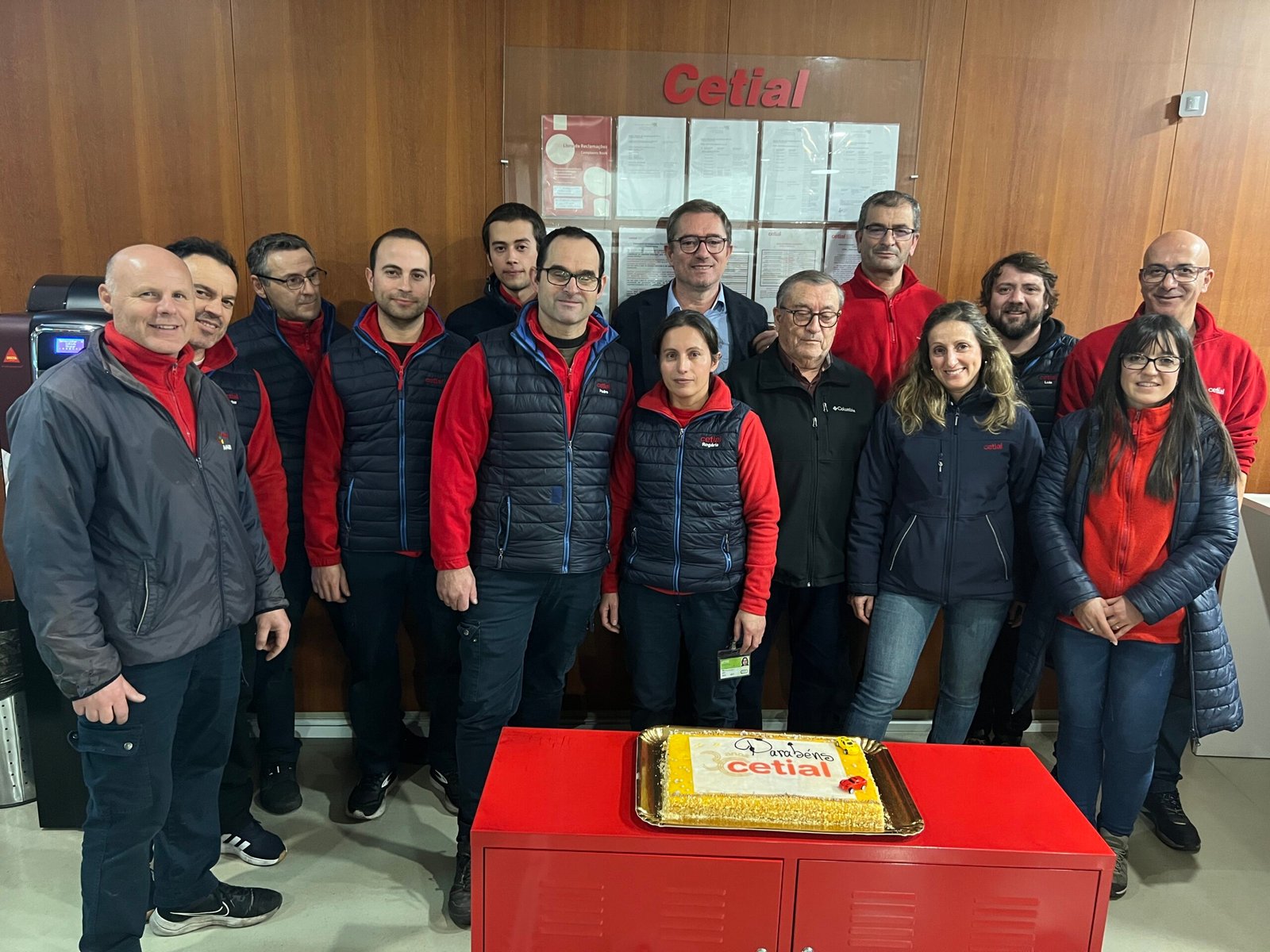 Equipa da cetial reunida no aniversário de 30 anos da empresa com um bolo na frente.
